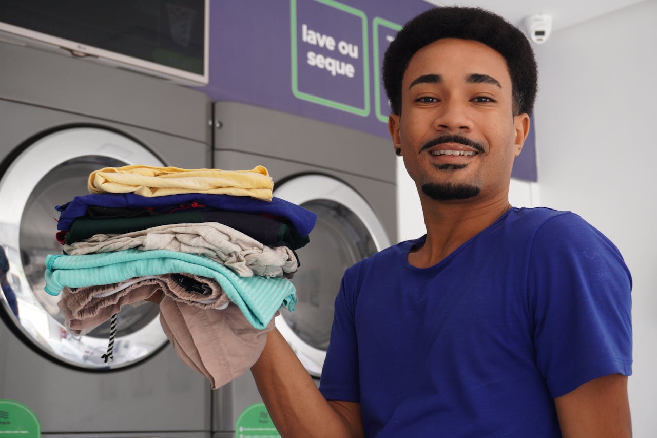 A happy man holding freshly washed clothes at a laundromat in Pernambuco, Brazil.